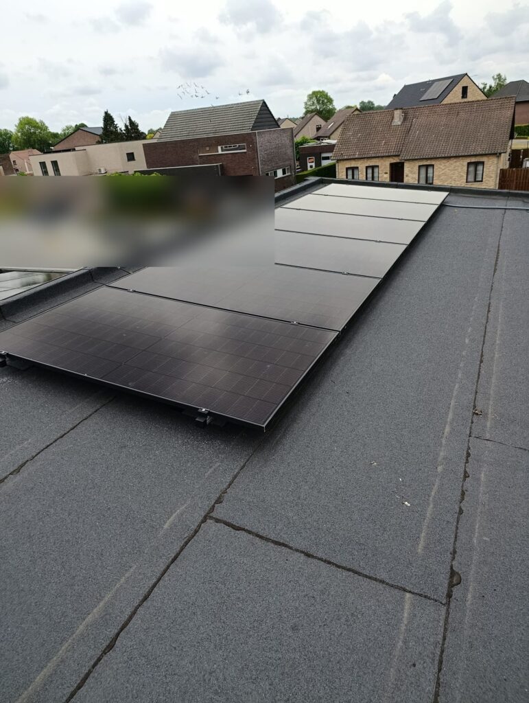 12 zonnepanelen met hybride omvormer op een plat dak in Maaseik